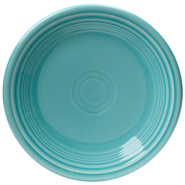 A close-up of a turquoise Fiesta salad plate with a circular pattern in the center.