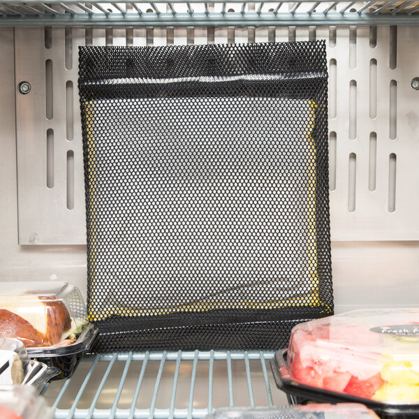 A black mesh bag with a yellow border in a refrigerator.