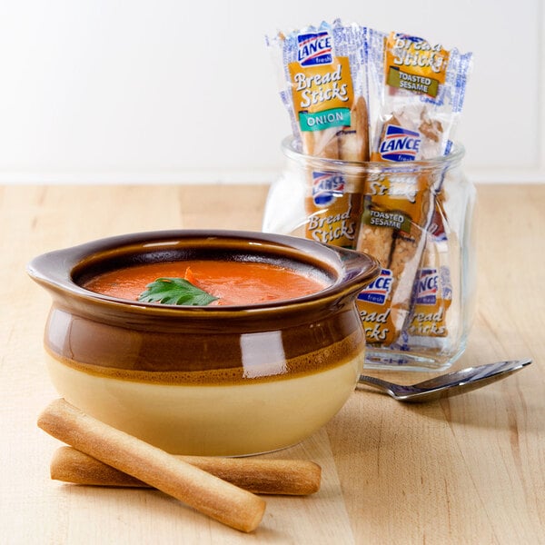 A bowl of soup next to Lance bread sticks.