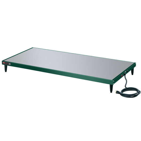 A green Hatco heated shelf warmer on a table with a cord.