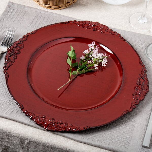 A Charge It by Jay red plastic charger plate with a flower on it.