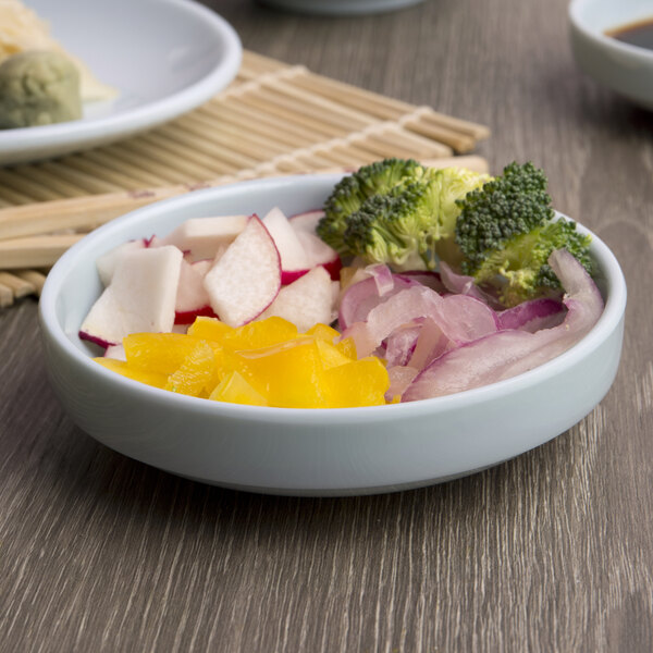 A bowl of food with vegetables and chopsticks in a Thunder Group Blue Jade melamine bowl.