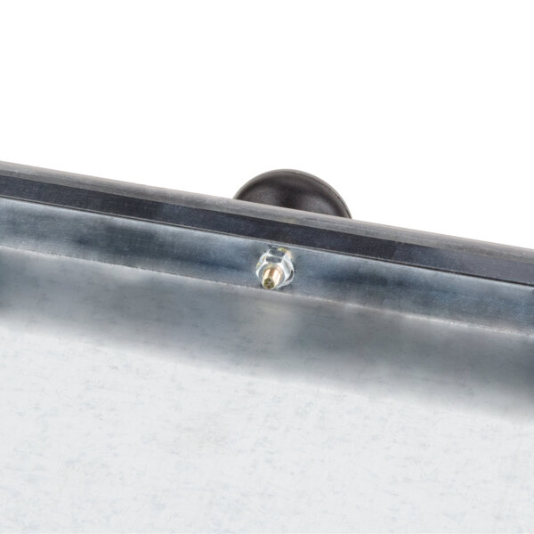 A close-up of a metal crumb tray with a screw on it.