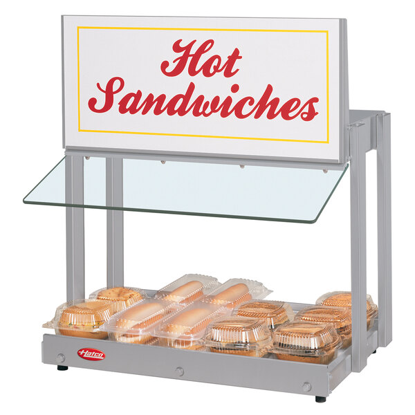 A Hatco mini-merchandising warmer with a sign that says "Hot Sandwiches" over hot sandwiches.