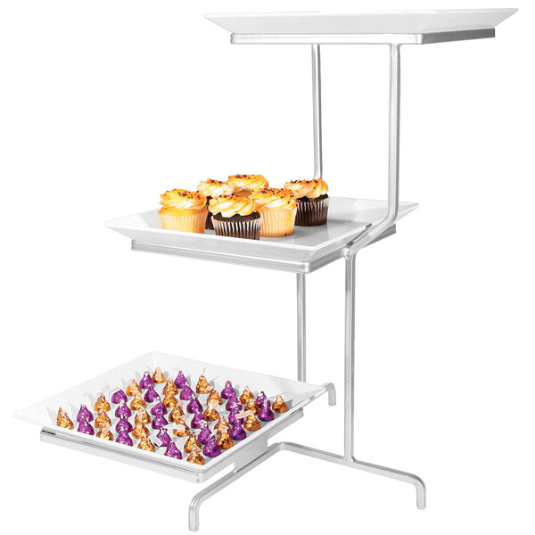 A Cal-Mil three tiered display stand with square melamine plates holding cupcakes on a table in a bakery.