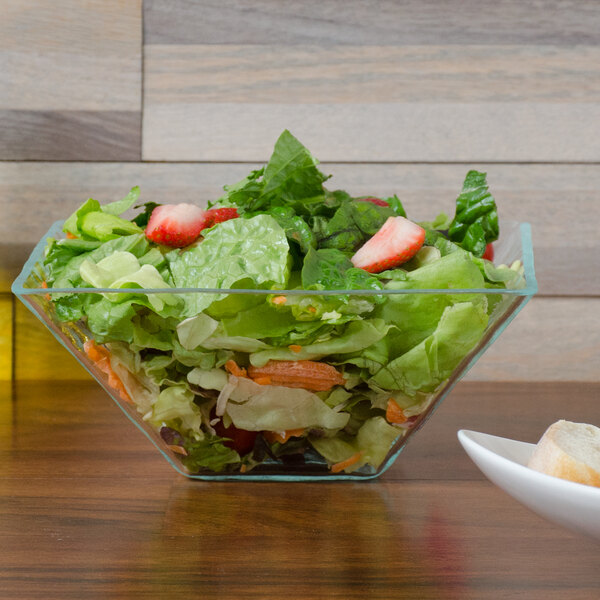 A clear Cal-Mil diamond bowl filled with salad on a table.