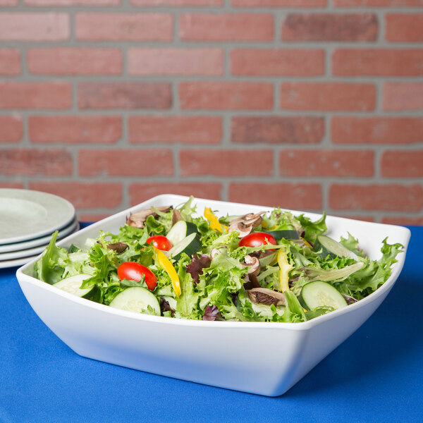 A white Cal-Mil melamine rounded square bowl filled with salad on a table.