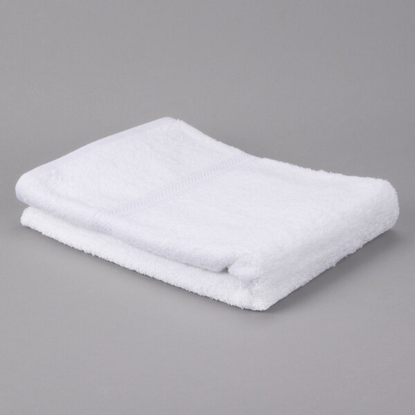 A white Oxford Gold bath towel on a gray surface.