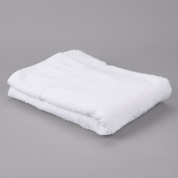 A folded white Oxford Gold Dobby bath towel on a gray surface.