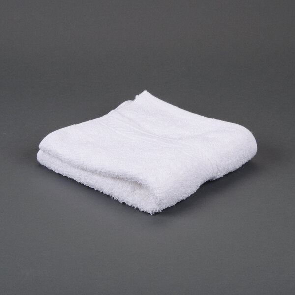 A folded white Oxford Gold Dobby hand towel on a gray surface.