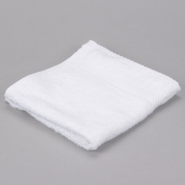 A white Oxford Signature wash cloth on a gray surface.