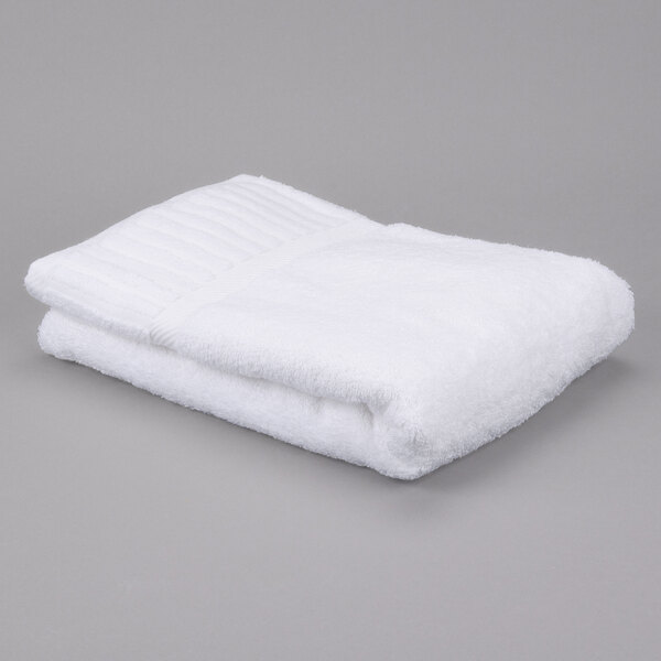 A white folded Oxford Signature bath towel on a gray surface.