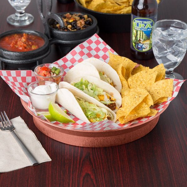 A table with a plate of tacos and a HS Inc. Paprika round deli server full of red sauce on a table in a Mexican restaurant.