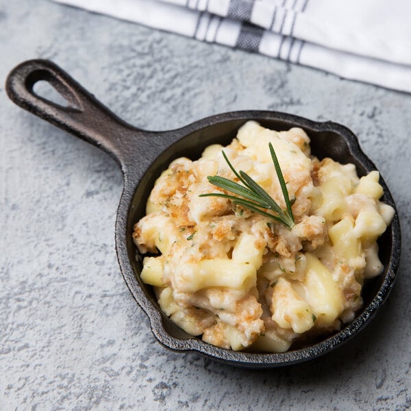 A Lodge mini cast iron skillet of macaroni and cheese with a rosemary sprig.