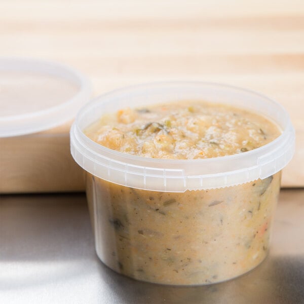 A clear 16 oz. tamper evident deli container of food on a table.