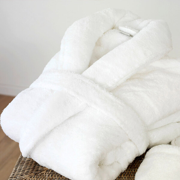 A pack of 12 white Oxford Velour bath robes on a wicker surface.