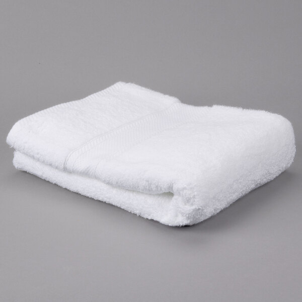 A white folded Oxford Miasma bath towel on a gray surface.