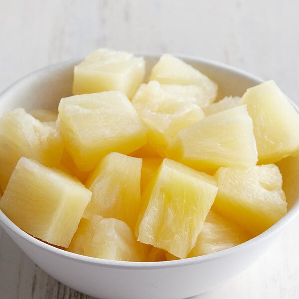 A bowl of Regal pineapple chunks on a white table.