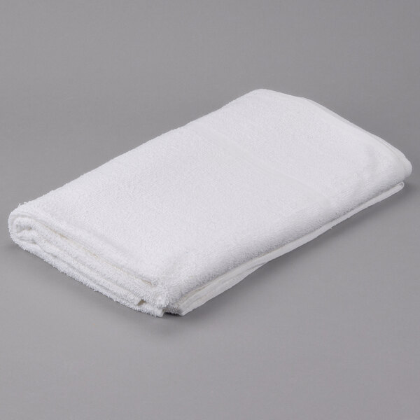 A folded white Oxford Bronze pool towel on a gray surface.