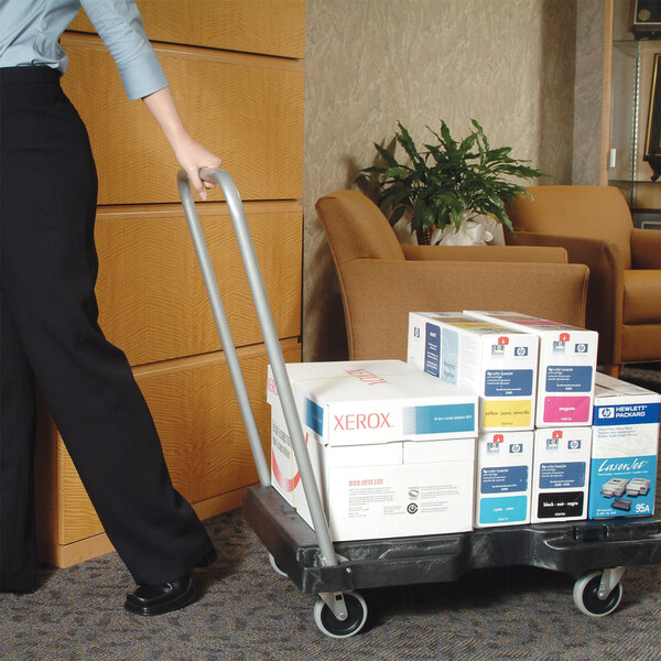 A woman pushing a Rubbermaid utility platform truck with boxes.