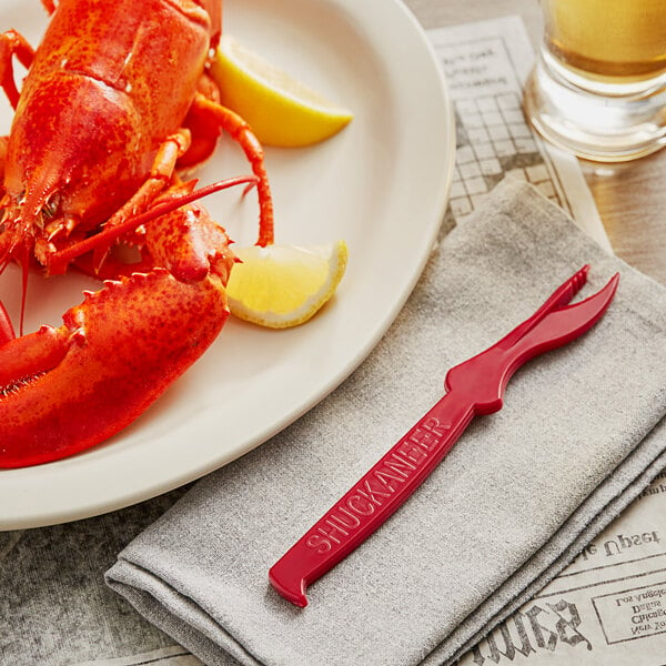 A lobster on a plate with a Choice Shuckaneer Red Seafood Sheller and lemon slices.
