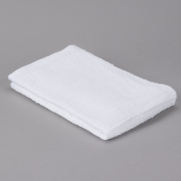 An Oxford Gold white bath towel with a cam border on a gray surface.