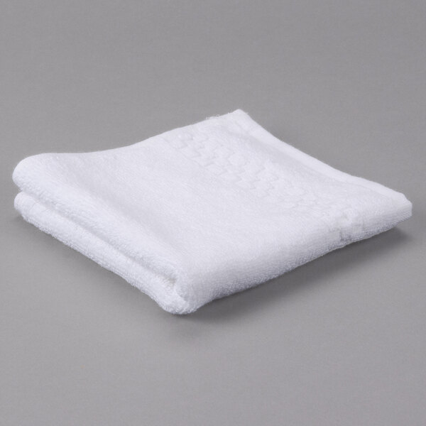 A folded white Oxford Viceroy wash cloth on a gray surface.