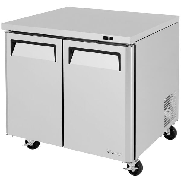 A white Turbo Air undercounter freezer with wheels and black handles.