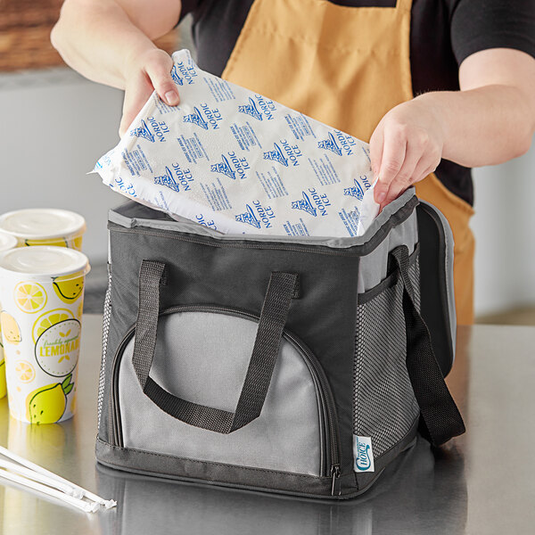 A woman opening a Choice black insulated cooler bag to reveal a drink inside.