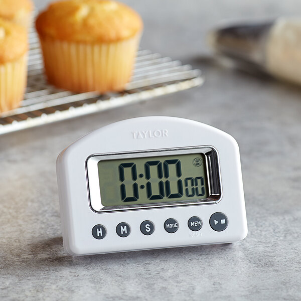 A Taylor digital kitchen timer on a counter with a muffin on the display.