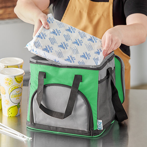 A woman opens a green and grey Choice insulated cooler bag to reveal a drink inside.