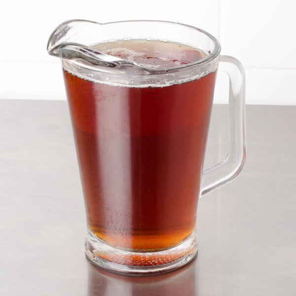 A glass pitcher of Bromley iced tea with a glass of brown liquid on the side.