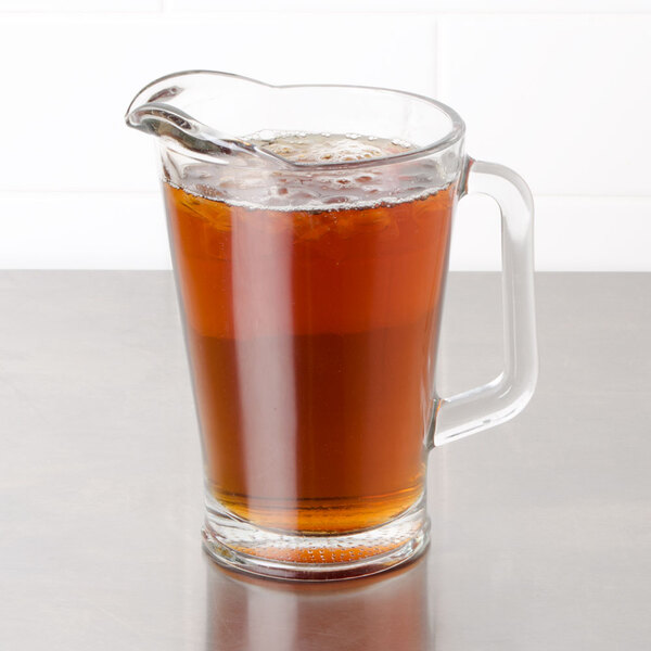 A glass pitcher of Bromley decaffeinated iced tea with a glass of tea on a table.