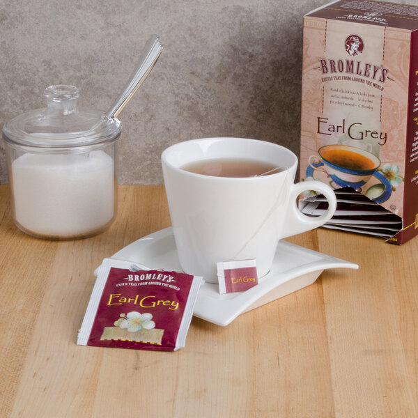 A box of Bromley Exotic Earl Grey Tea on a counter next to a cup of tea with a tea bag in it.