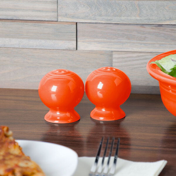 A Fiesta poppy salt and pepper shaker set on a table with bowls and a salad