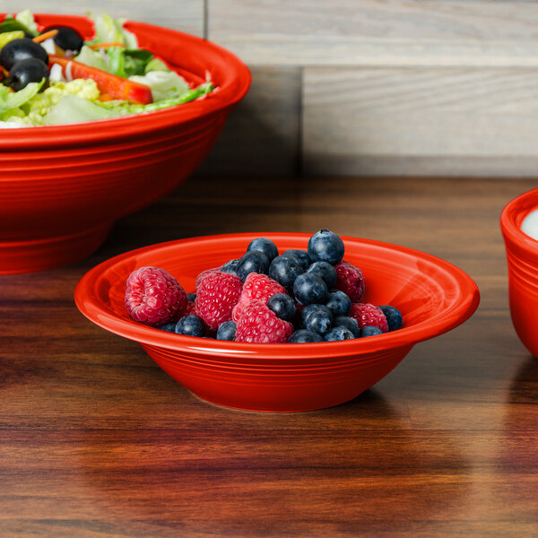A red Fiesta china bowl filled with blueberries and raspberries.