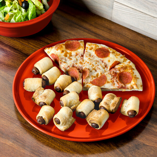 A Fiesta china pizza tray holding pizza and rolls of sausage on a table.