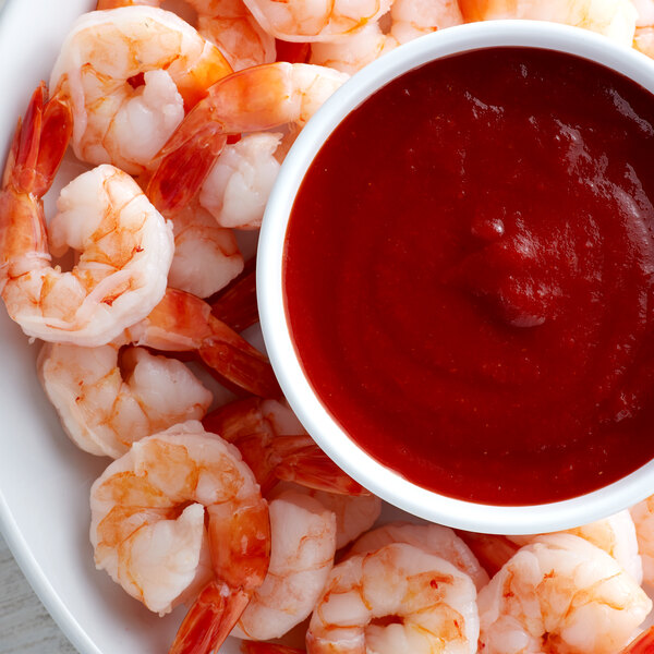 A plate of shrimp with a bowl of Furmano's chili sauce.