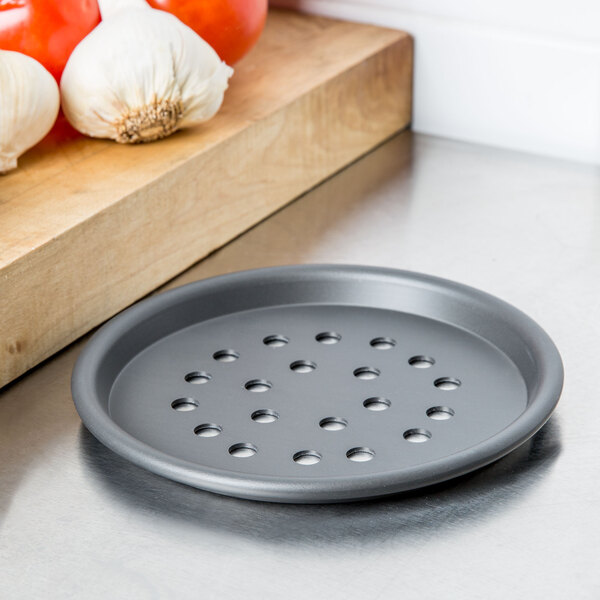 An American Metalcraft super perforated hard coat anodized aluminum pizza pan with holes on a white surface.
