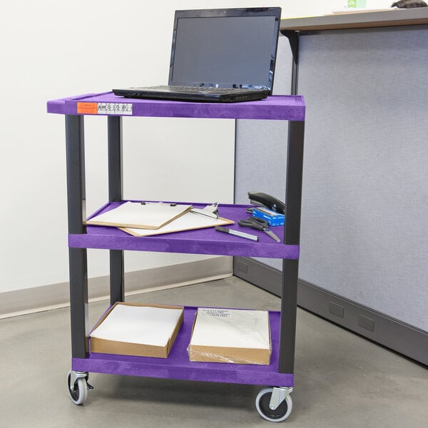 A purple Luxor utility cart with a laptop on a shelf.