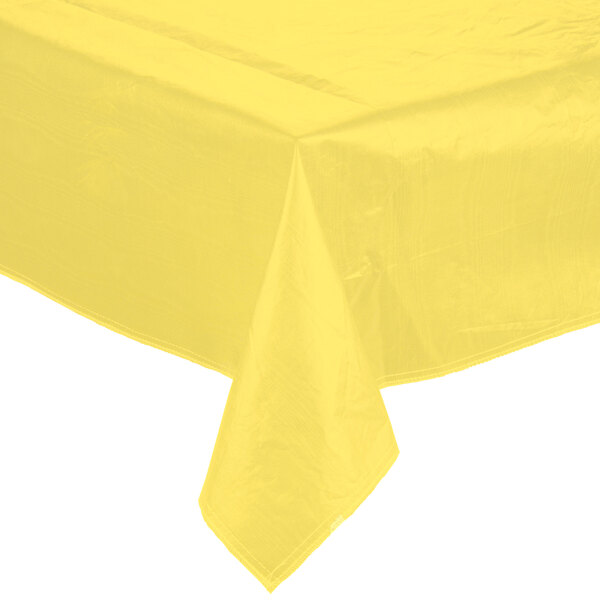 A yellow vinyl tablecloth with a crease on a table.