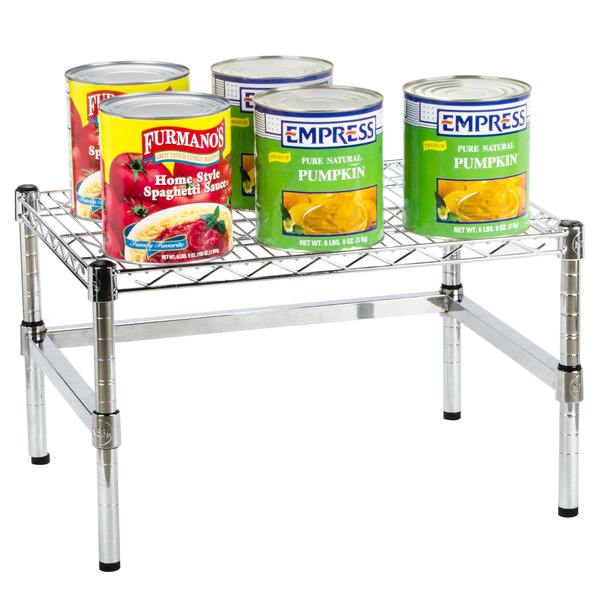 A Regency chrome plated wire dunnage rack with cans of pumpkin soup and spaghetti sauce on it.