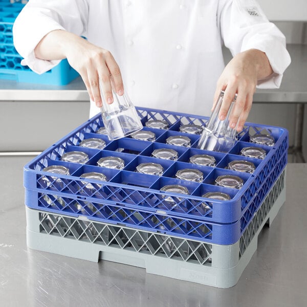 A woman using a gray Noble Products glass rack with blue extenders to store glasses.