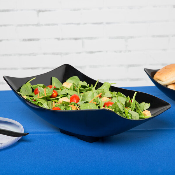 A San Michele black melamine salad bowl with tomatoes and spinach.