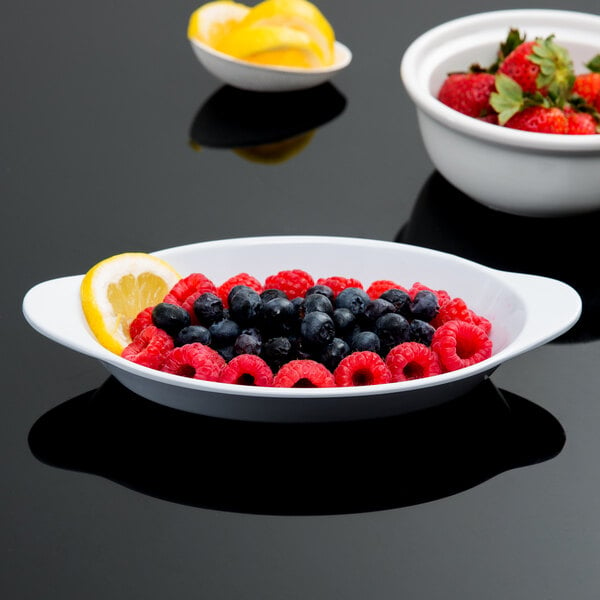 A white GET oval side dish filled with blueberries, raspberries, and strawberries.