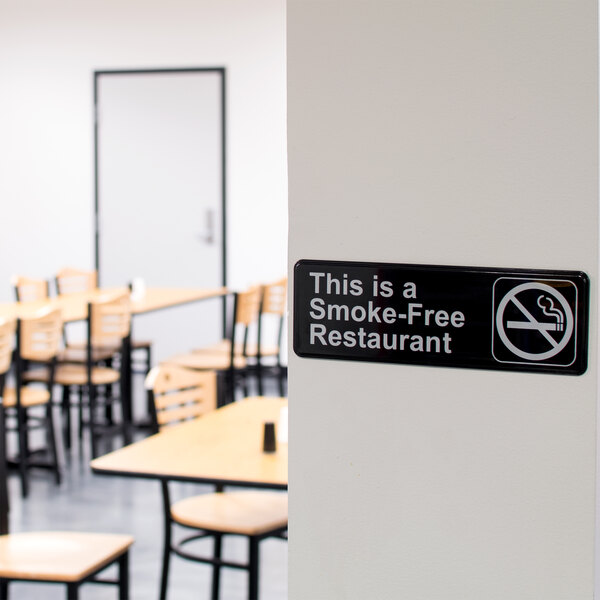 A black and white Thunder Group sign that says "This is a smoke-free restaurant" on a wall.