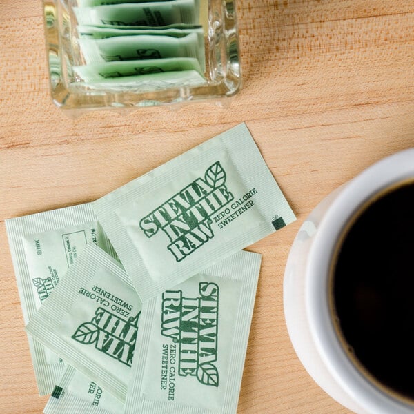 A cup of coffee with Stevia In The Raw packets on a table.