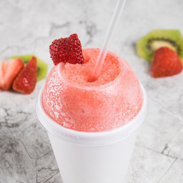 A Dart clear plastic dome lid with a straw hole on a cup of strawberry slushy.