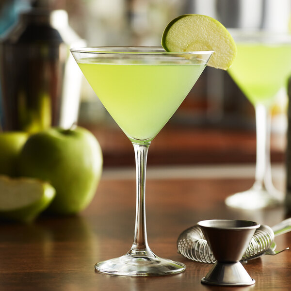 A Libbey martini glass filled with green liquid and a slice of apple on the rim.