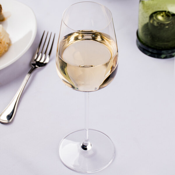 A close up of a Spiegelau Willsberger white wine glass full of wine on a table.